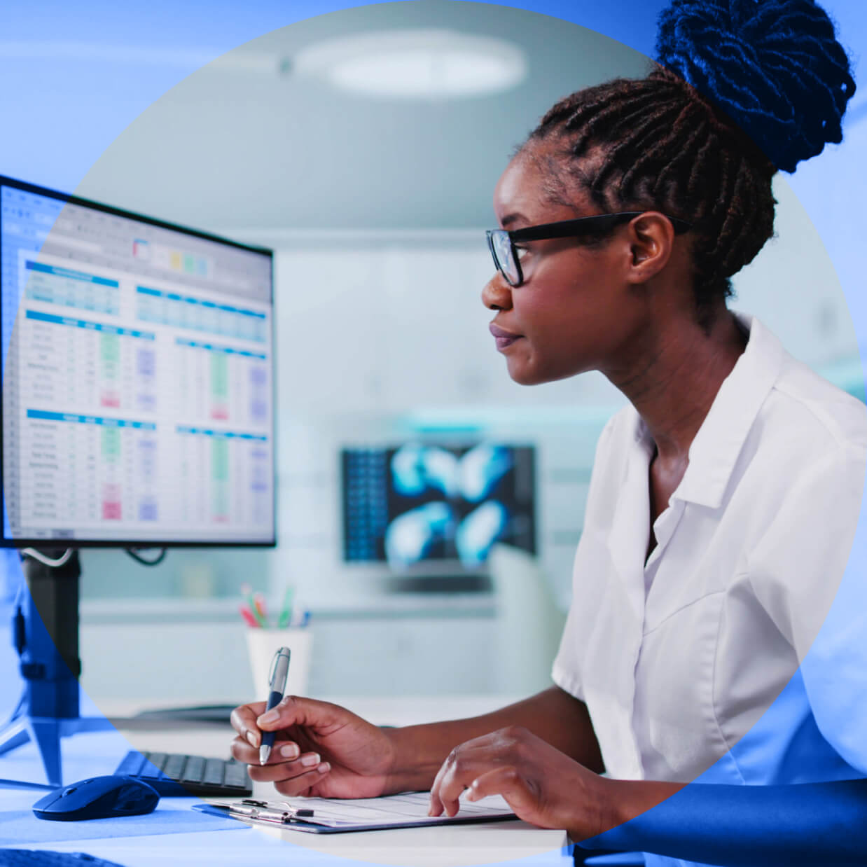 Doctor using a computer and writing down information